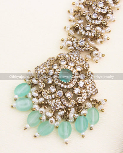 Close-up of mint green Victorian maang tikka with shimmering CZ stones and pearl drops.