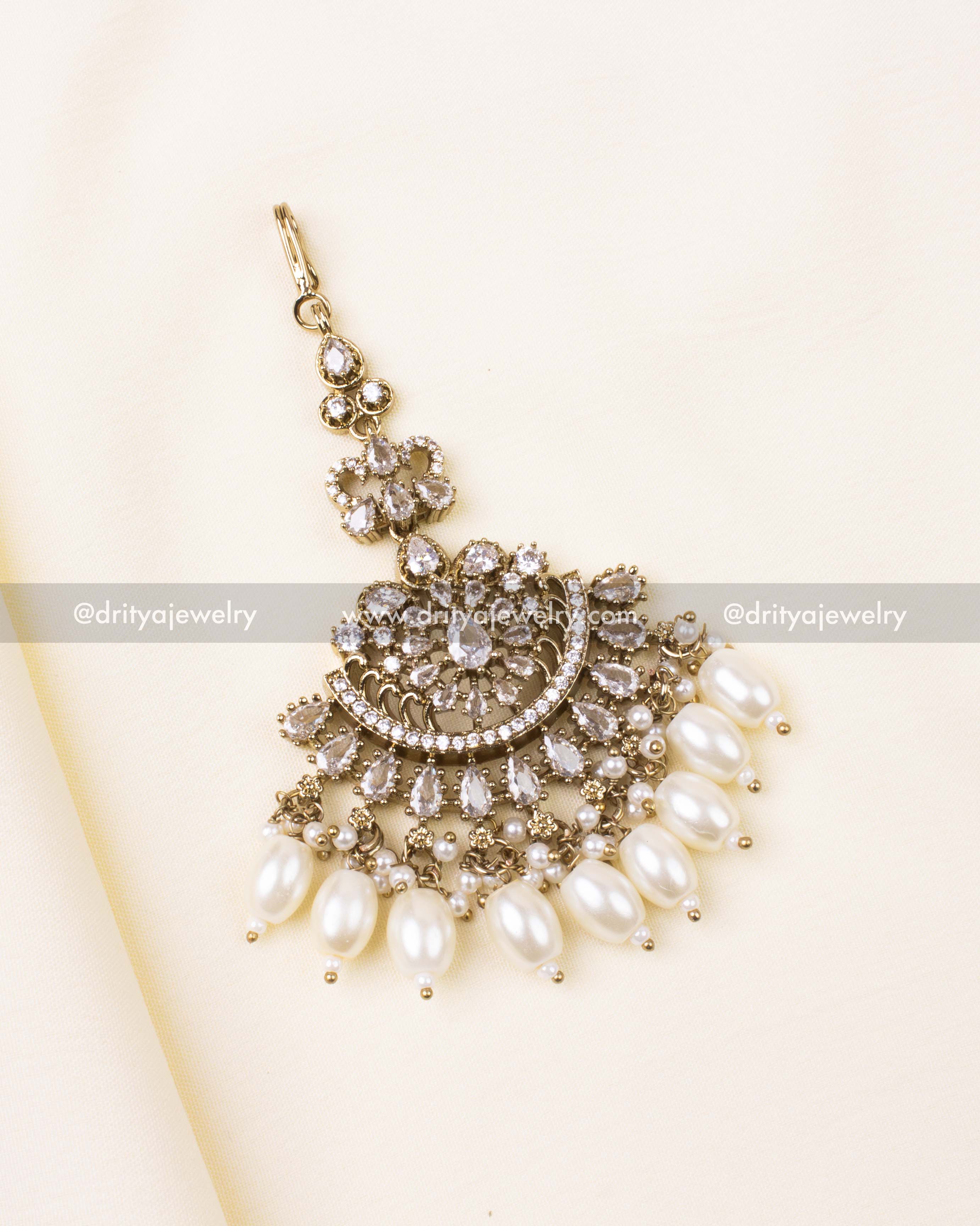 White-stone Victorian-style maang tikka with pearl drops in antique gold finish.