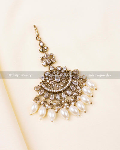 White-stone Victorian-style maang tikka with pearl drops in antique gold finish.