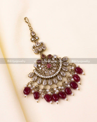 Maang tikka in ruby red with pearl detailing and antique gold design.