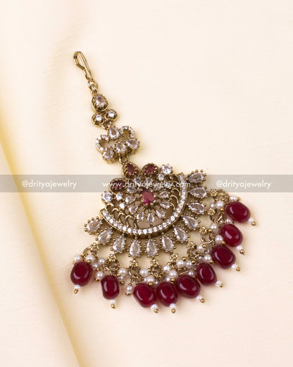 Maang tikka in ruby red with pearl detailing and antique gold design.