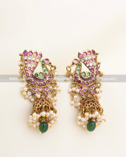 Stone-studded peacock earrings featuring kundan work, pearl clusters, and green bead drop.