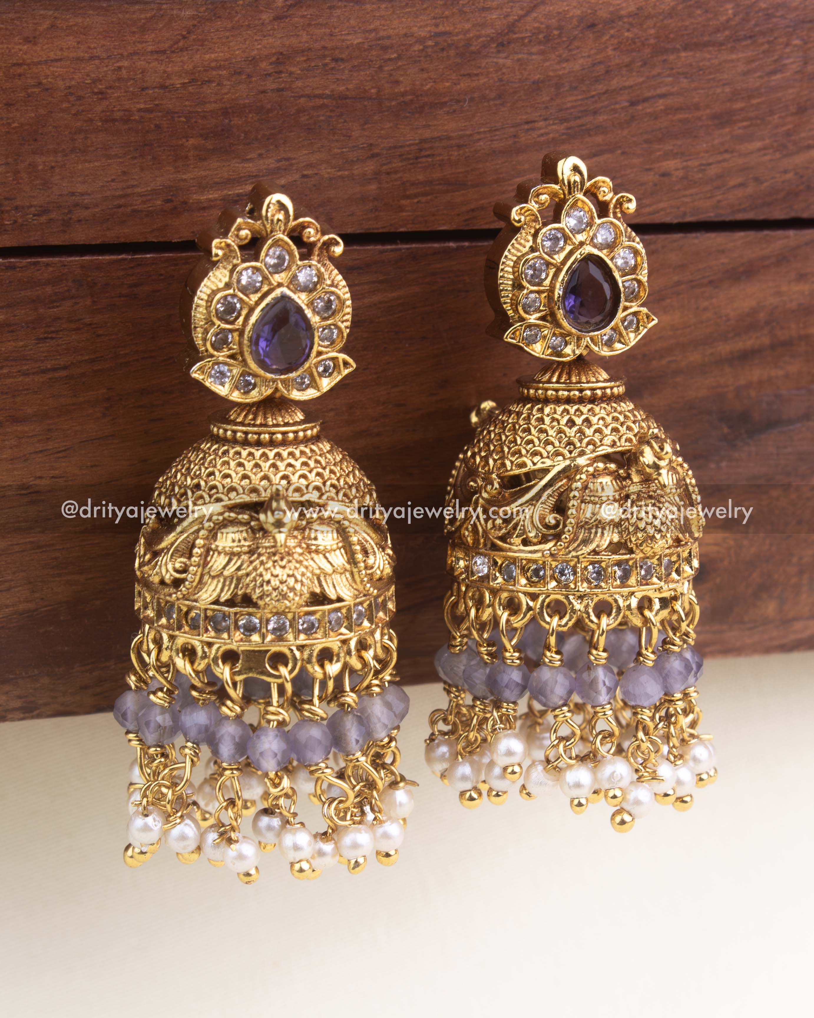 Antique temple-style jhumka featuring purple tear-drop stone, faceted beads, and intricate gold carving.