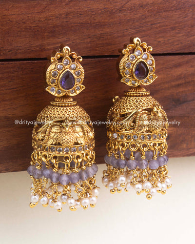 Antique temple-style jhumka featuring purple tear-drop stone, faceted beads, and intricate gold carving.