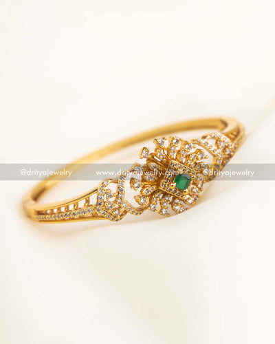 Close-up of floral CZ setting with emerald green square stone at the center.