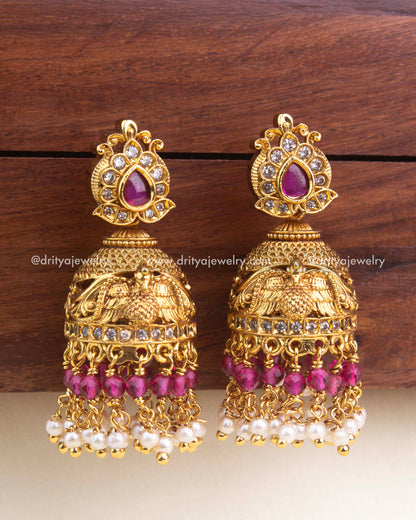 Premium antique jhumka featuring ruby tear-drop stone, gold detailing, and dual-layer bead hangings.