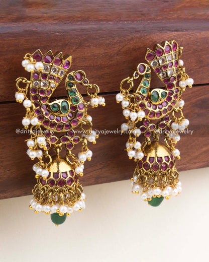 Premium gold-finish peacock dangler earrings with ruby and emerald stones, mini jhumka, and pearl drops.