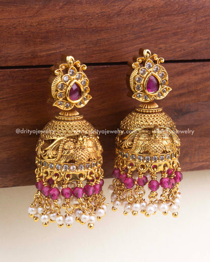 Antique-style jhumka with ruby red stones, carved bird design, red beads, and pearl danglers.