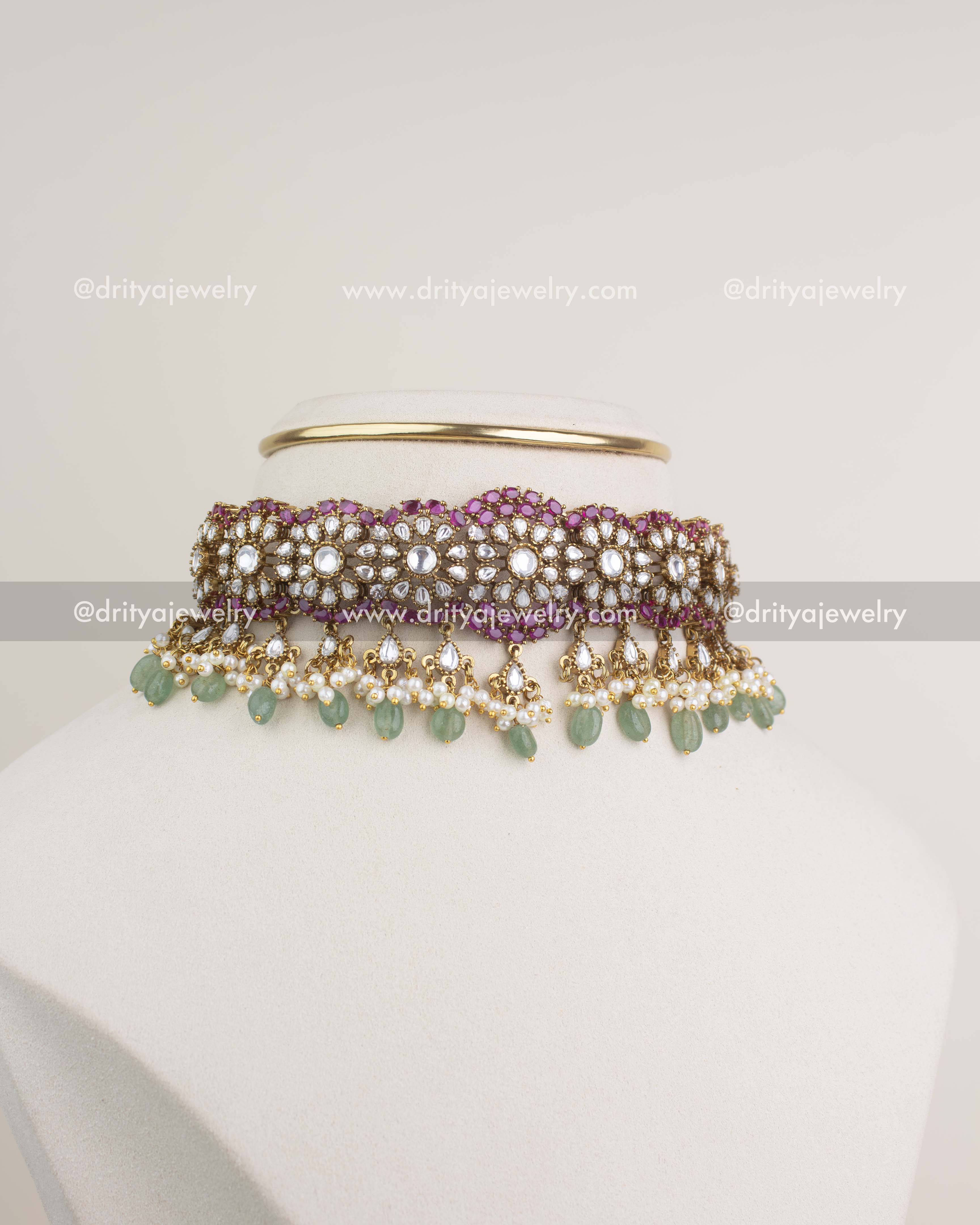 Premium polki kundan choker set with ruby border and green bead drops displayed on a mannequin.