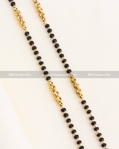 Close-up of dual-strand black beads necklace with textured gold beads and traditional design.