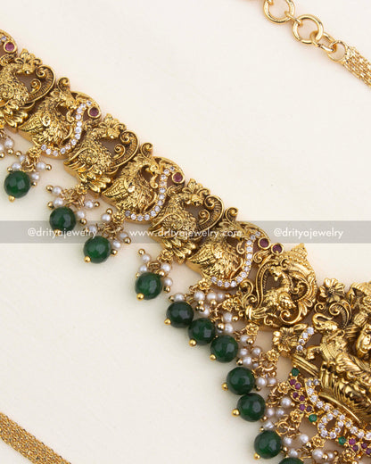 Close-up of nakshi peacock carvings with pearl clusters and emerald bead drops.