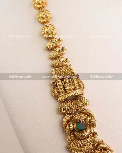 Close-up of intricate Nakshi carvings, peacock motifs, and green stone detailing in temple necklace.