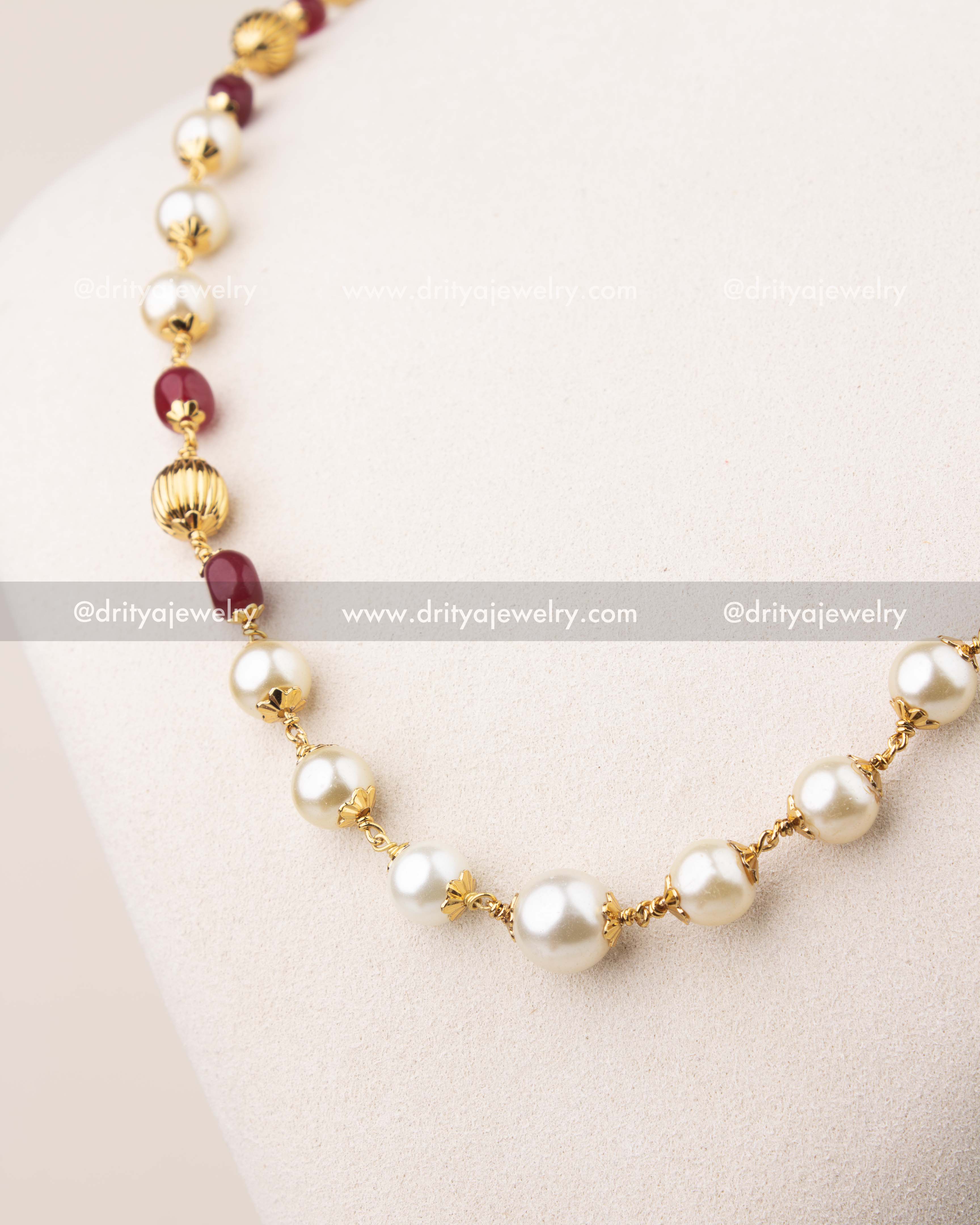 Close-up of pearl beads mala necklace featuring ruby-colored beads and gold detailing