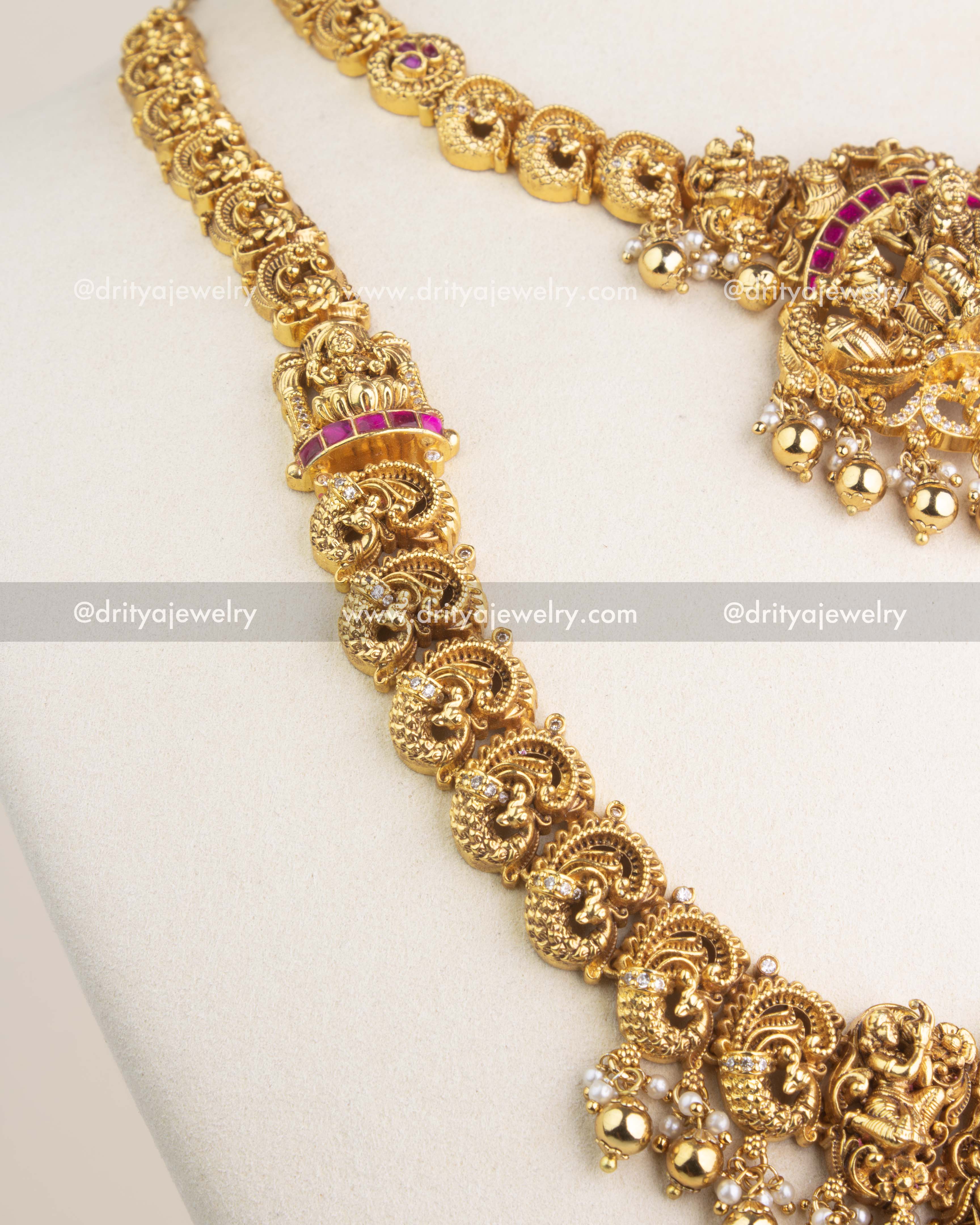 Detailed view of Lakshmi motif pendant with ruby kemp stones, peacock carvings, and pearl drops.