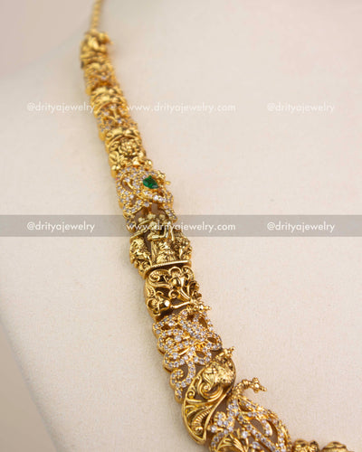 Intricate Nakshi chain design with miniature figurines, carvings, and green stone accents.