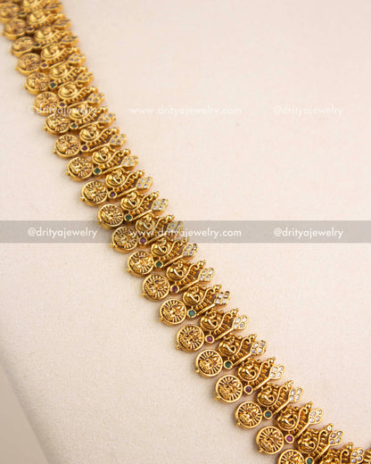 Close-up view of intricate peacock and coin-patterned chain design in antique gold finish.