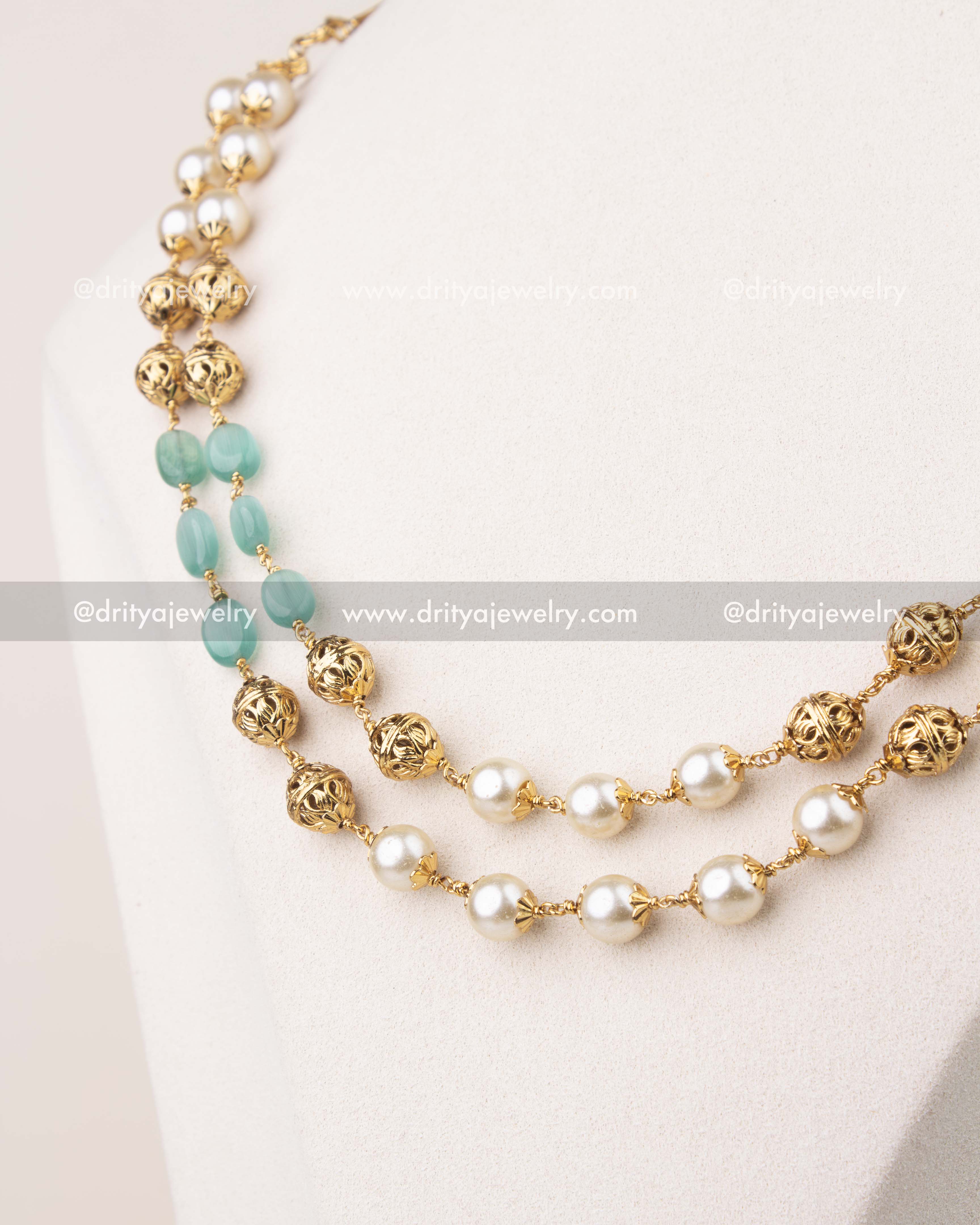 Close-up of mint green beads and pearls with gold polish detailing in layered mala necklace