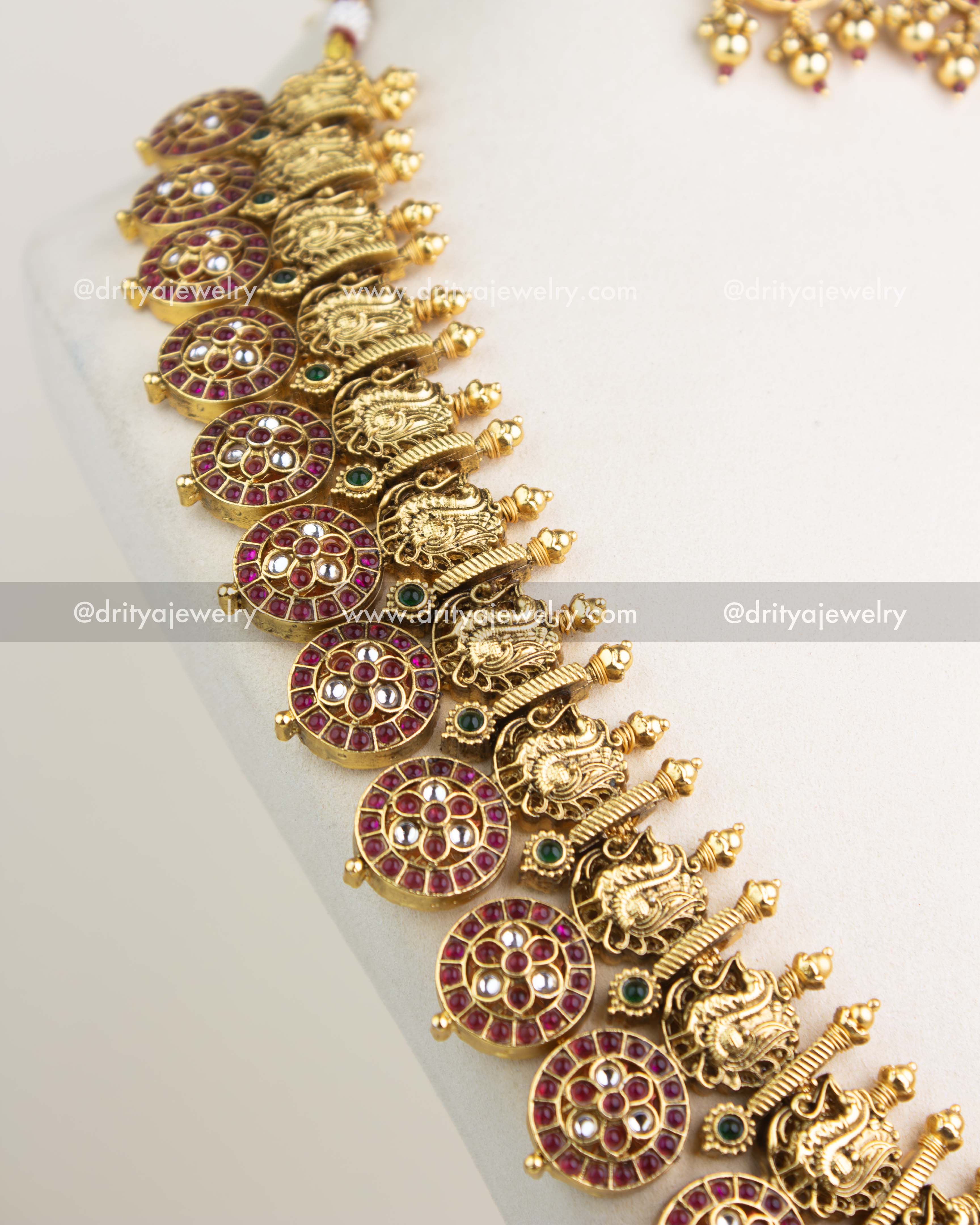 Close-up of Bottu Mala showing peacock motifs, ruby Bottu discs, and intricate kundan detailing.