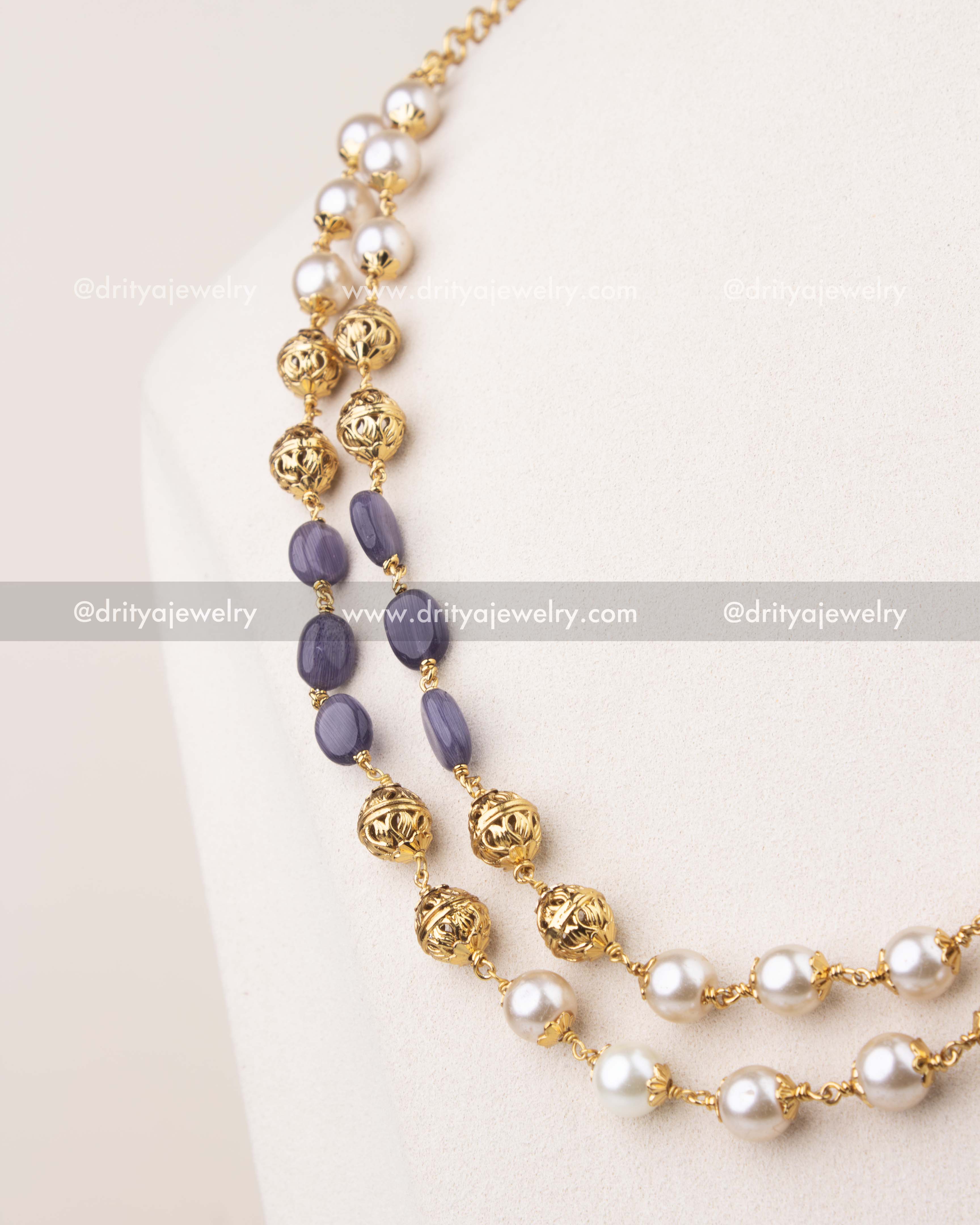 Close-up of purple beads and pearls with intricate gold polish work in layered mala necklace
