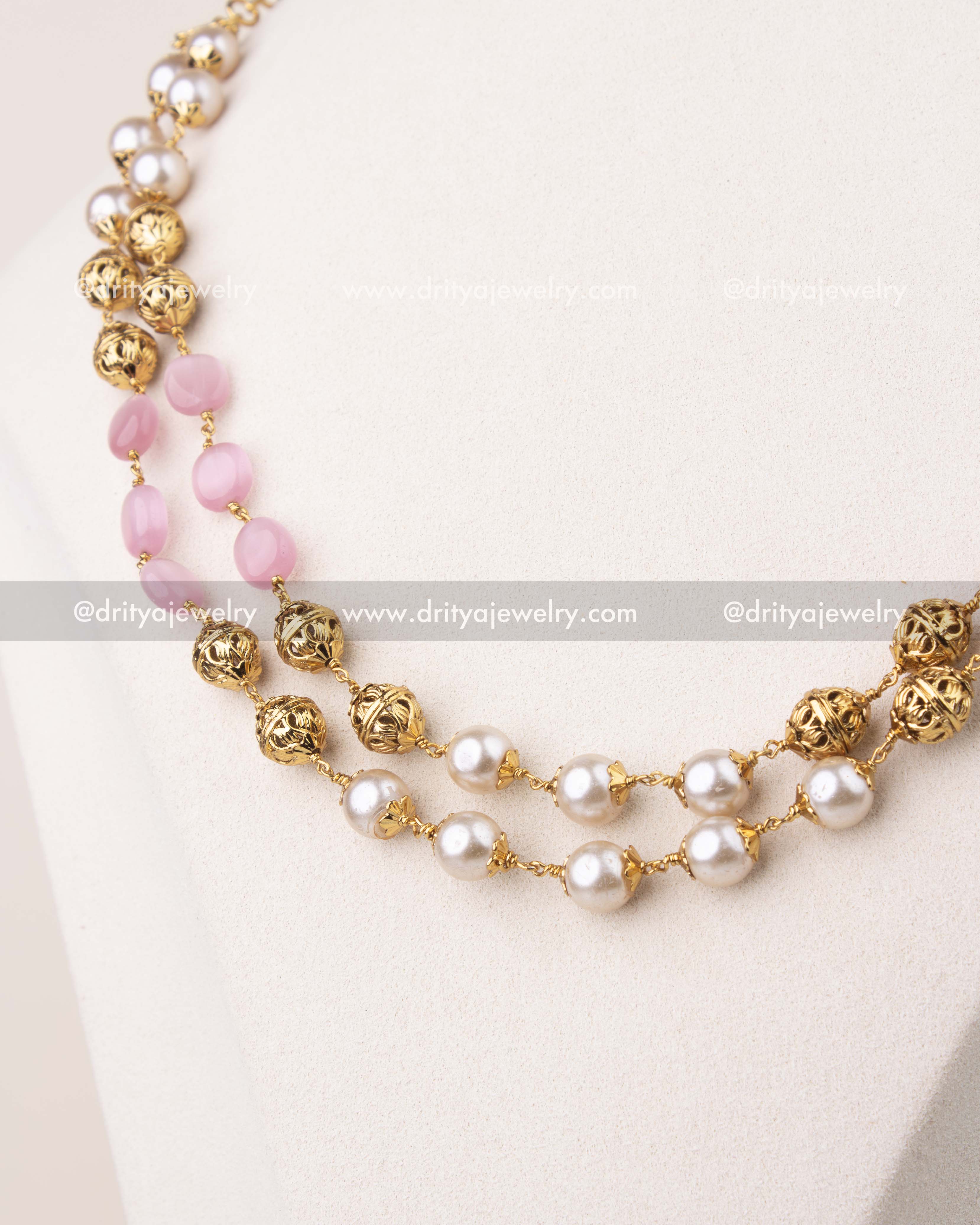 Close-up of blush pink beads and pearls with gold polish detailing in layered mala necklace