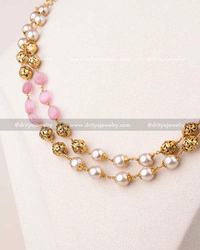 Close-up of blush pink beads and pearls with gold polish detailing in layered mala necklace