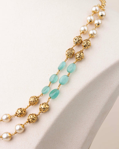 Close-up of mint green beads and pearls with gold polish detailing in layered mala necklace