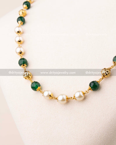 Close-up of pearl and emerald beads mala with gold-toned spacer detailing