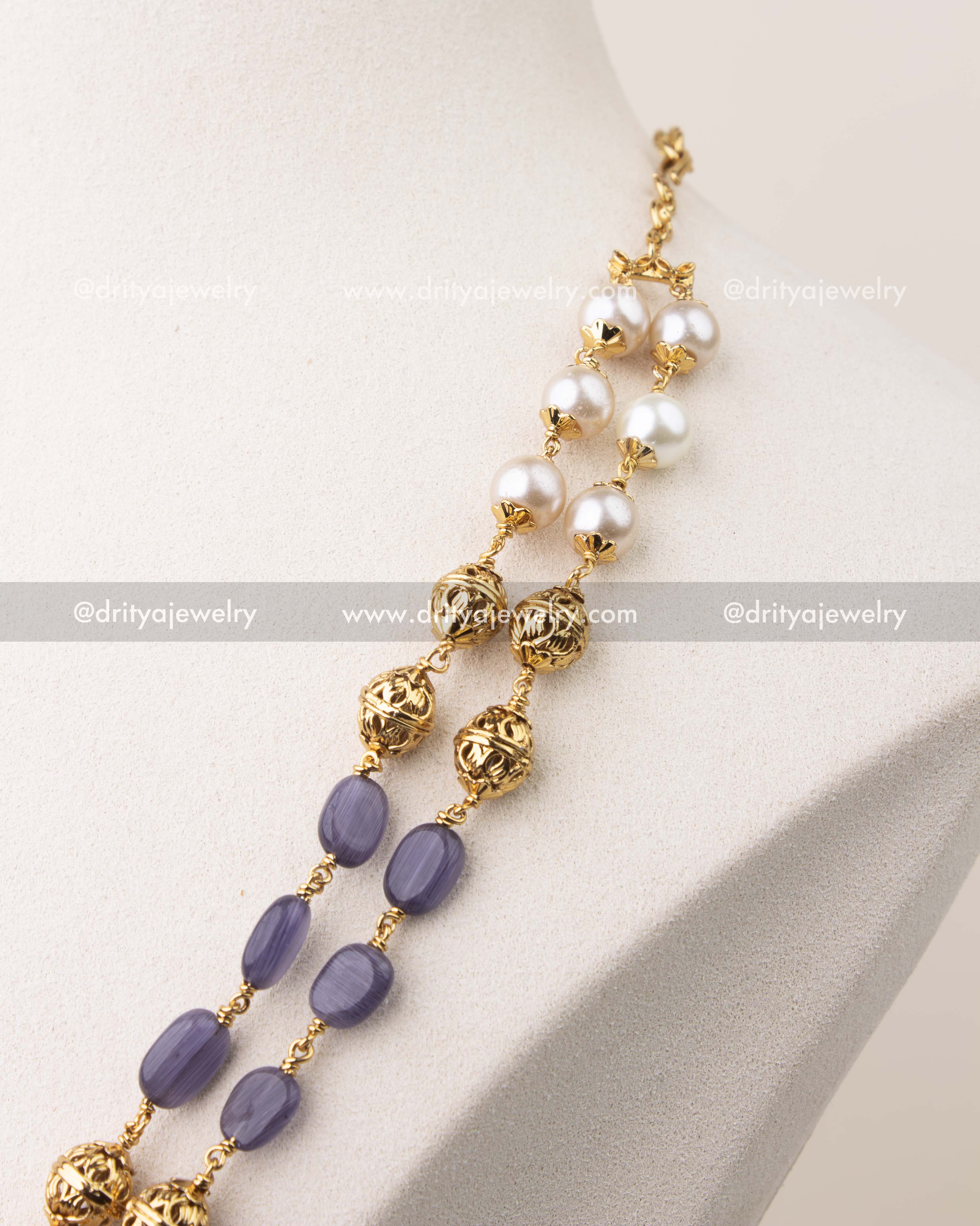 Close-up of purple beads and pearls with intricate gold polish work in layered mala necklace