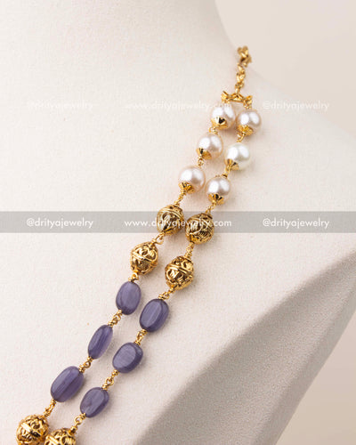 Close-up of purple beads and pearls with intricate gold polish work in layered mala necklace