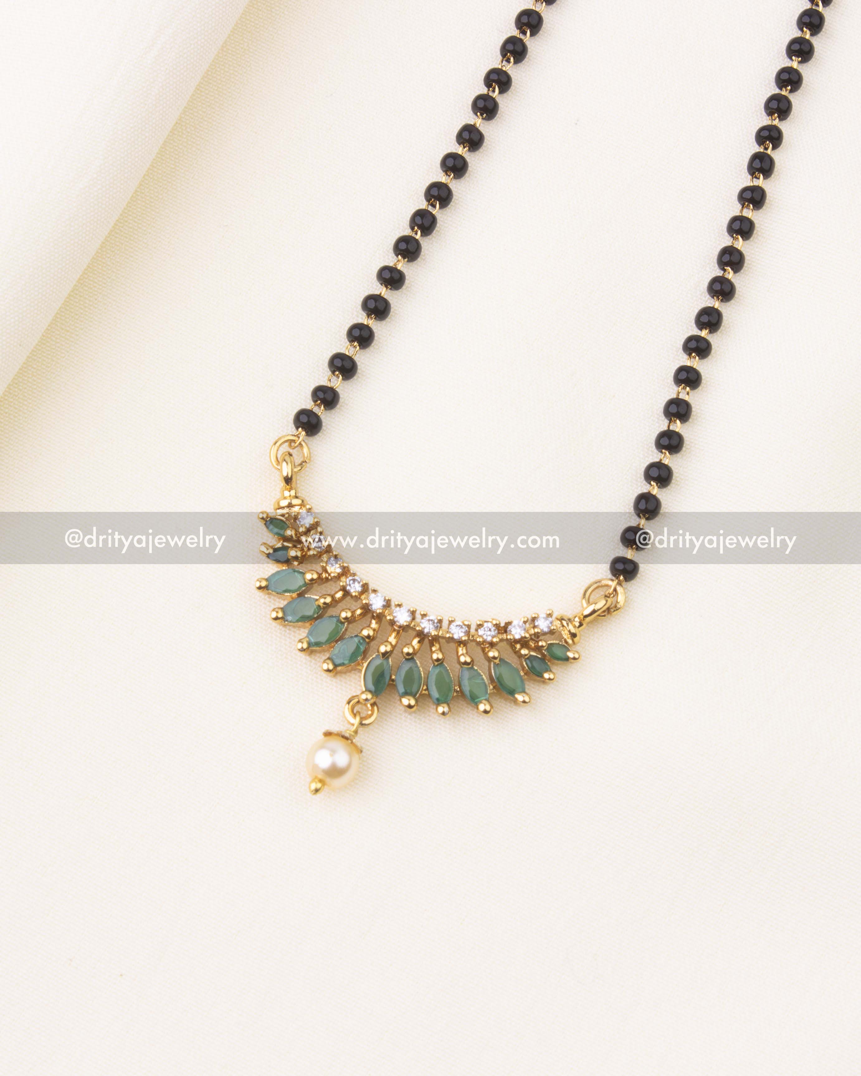 Detailed view of green-studded pendant with pearl drop on black beads chain.