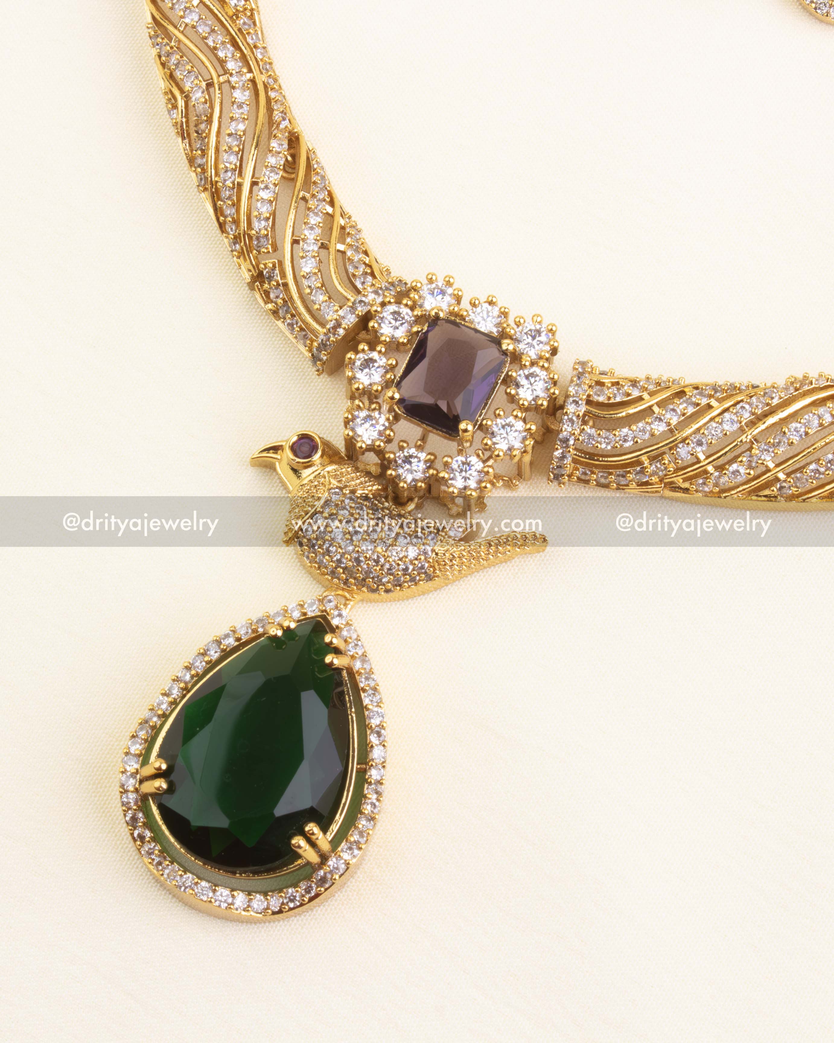 Close-up of the bird motif necklace pendant with violet and green stones surrounded by CZs