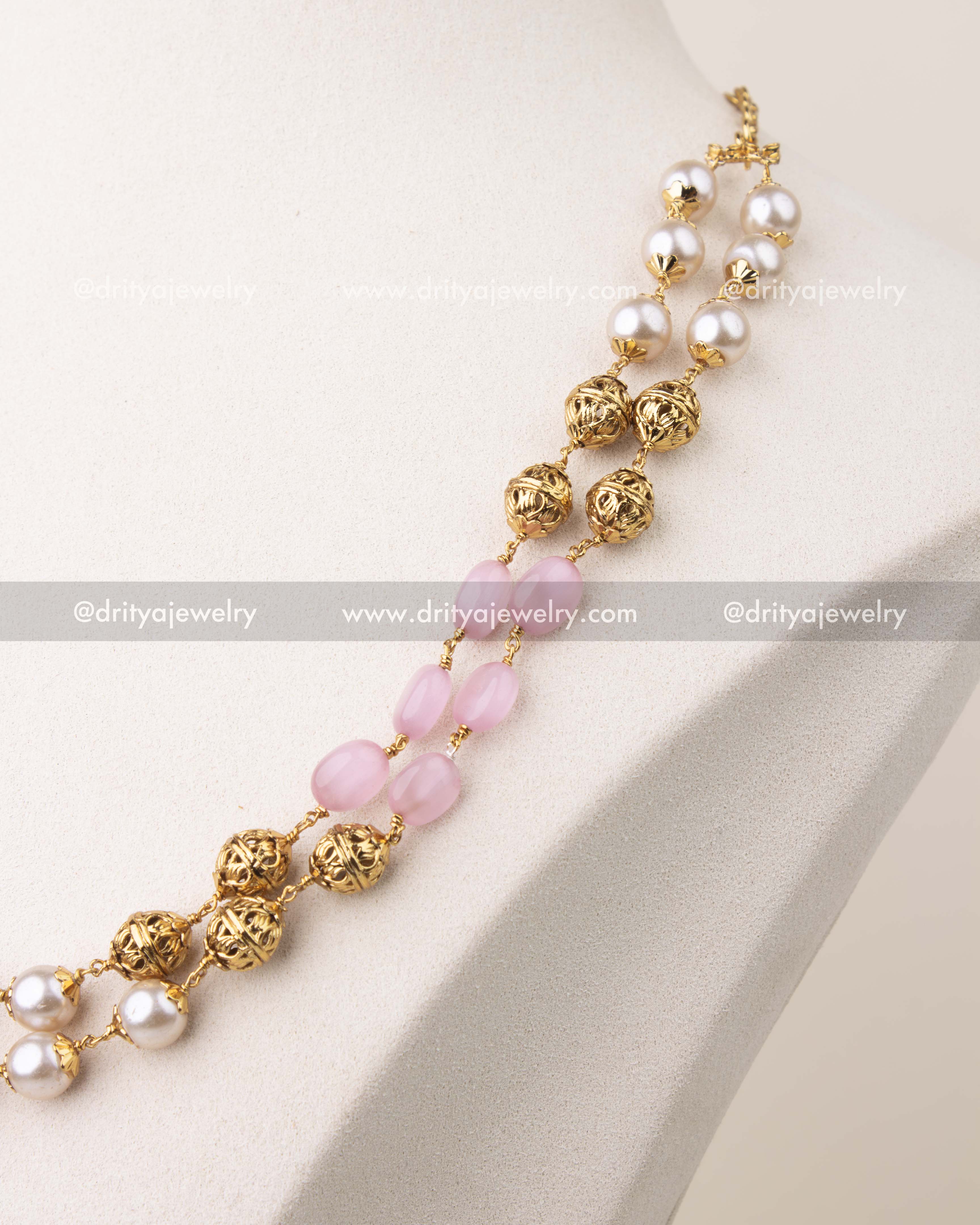 Close-up of blush pink beads and pearls with gold polish detailing in layered mala necklace