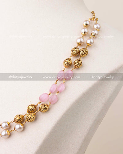 Close-up of blush pink beads and pearls with gold polish detailing in layered mala necklace