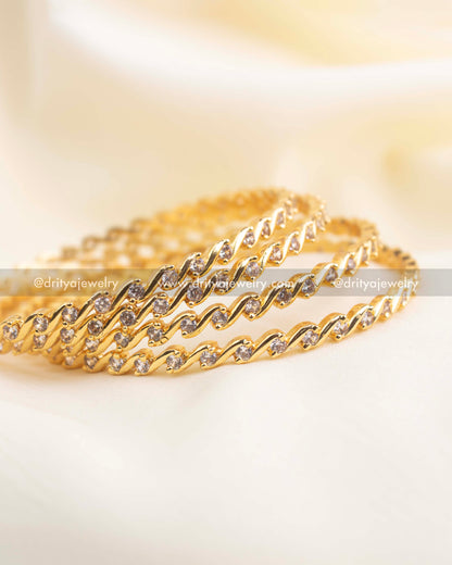 Close-up of wave-design CZ bangles showcasing detailed stone placement and gold finish.