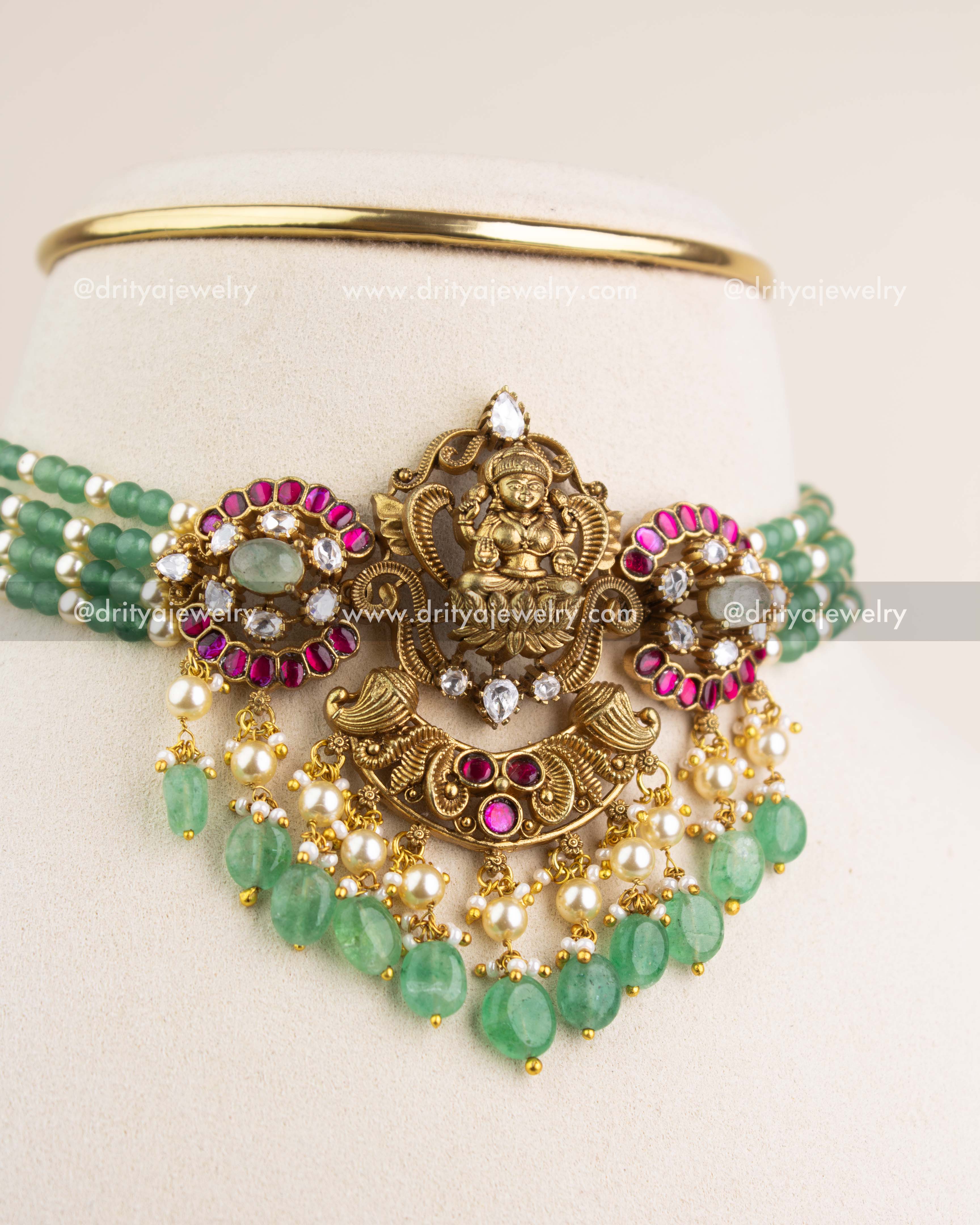 Intricate Lakshmi Devi temple pendant with kemp stones, kundan work, pearls, and green drops.