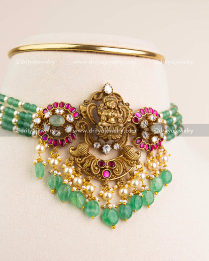 Intricate Lakshmi Devi temple pendant with kemp stones, kundan work, pearls, and green drops.