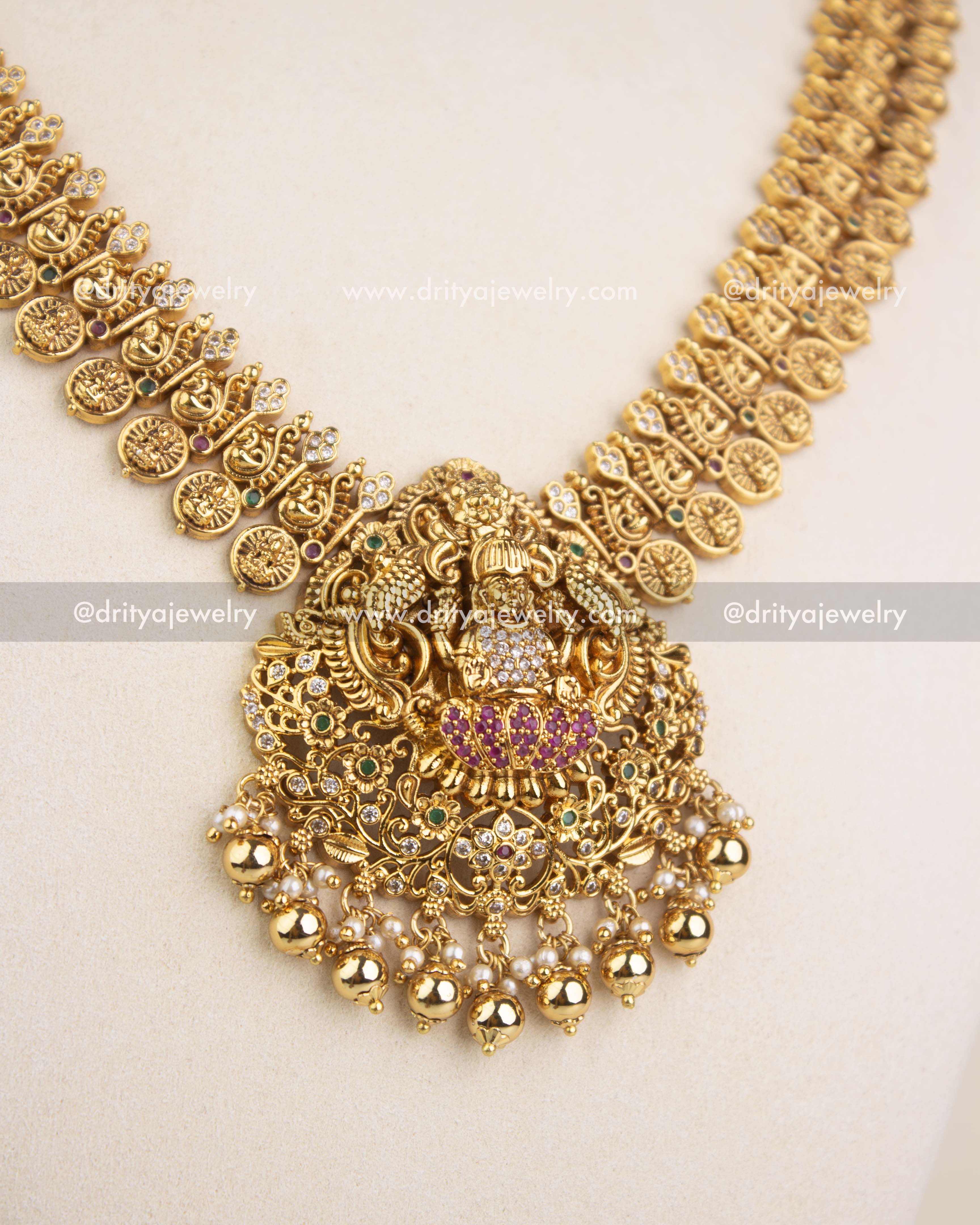 Detailed close-up of Lakshmi pendant with ruby, emerald accents and pearl drops.