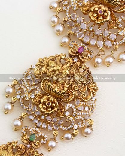 Intricate peacock and floral carvings with ruby and emerald stones in antique gold polish.