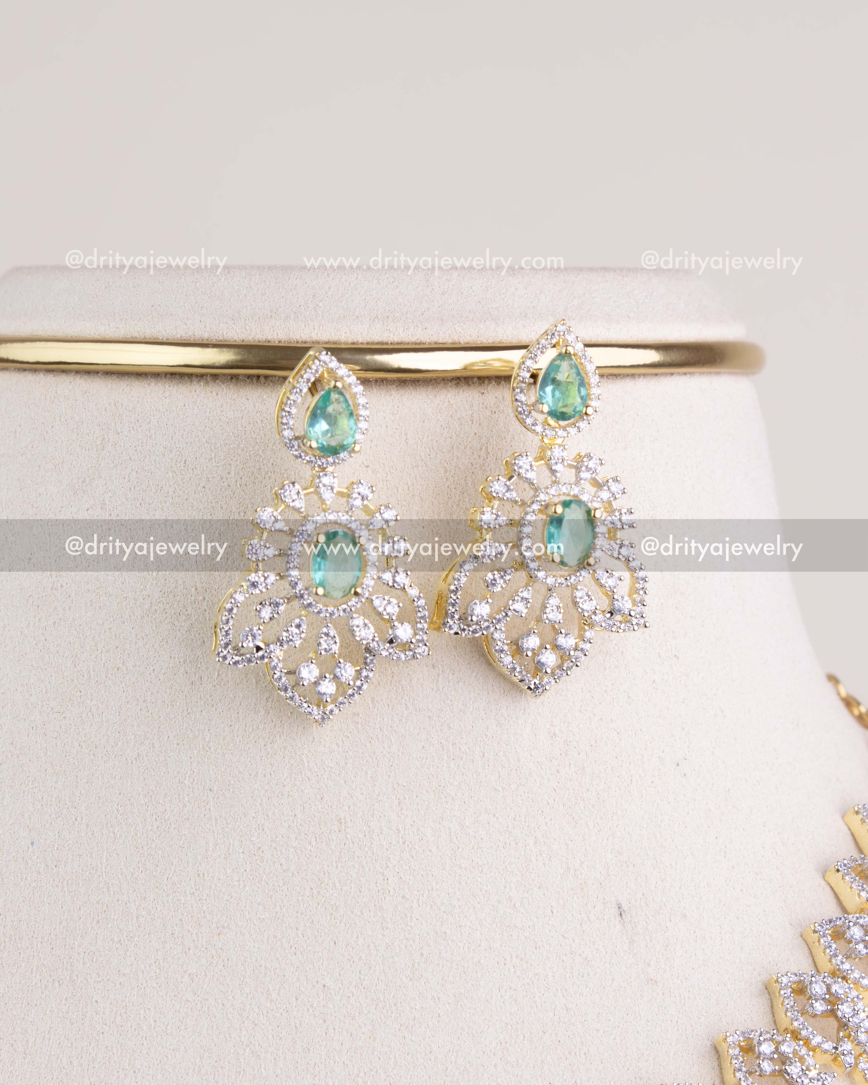 1232-RE close-up of green stone cz studded dangler earrings on display stand