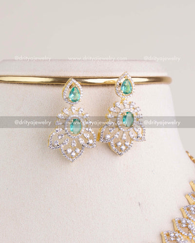 1232-RE close-up of green stone cz studded dangler earrings on display stand