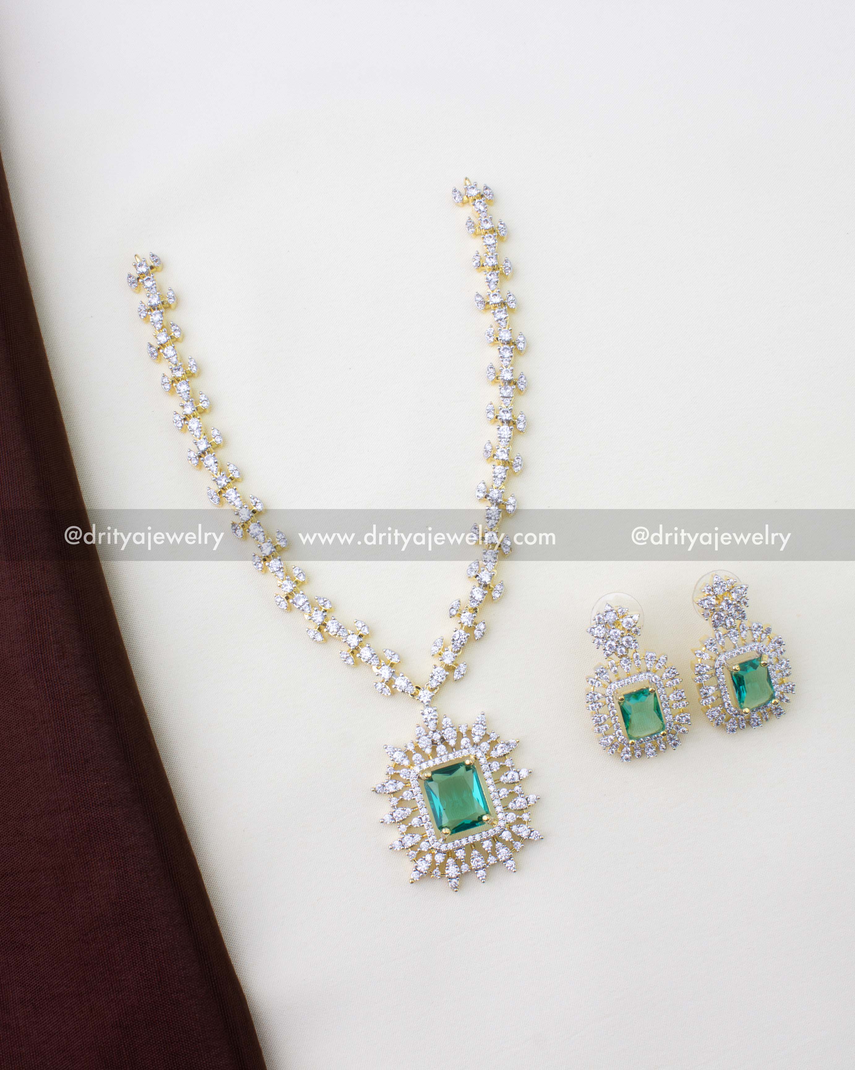 1276-RE premium emerald necklace set with matching earrings laid flat