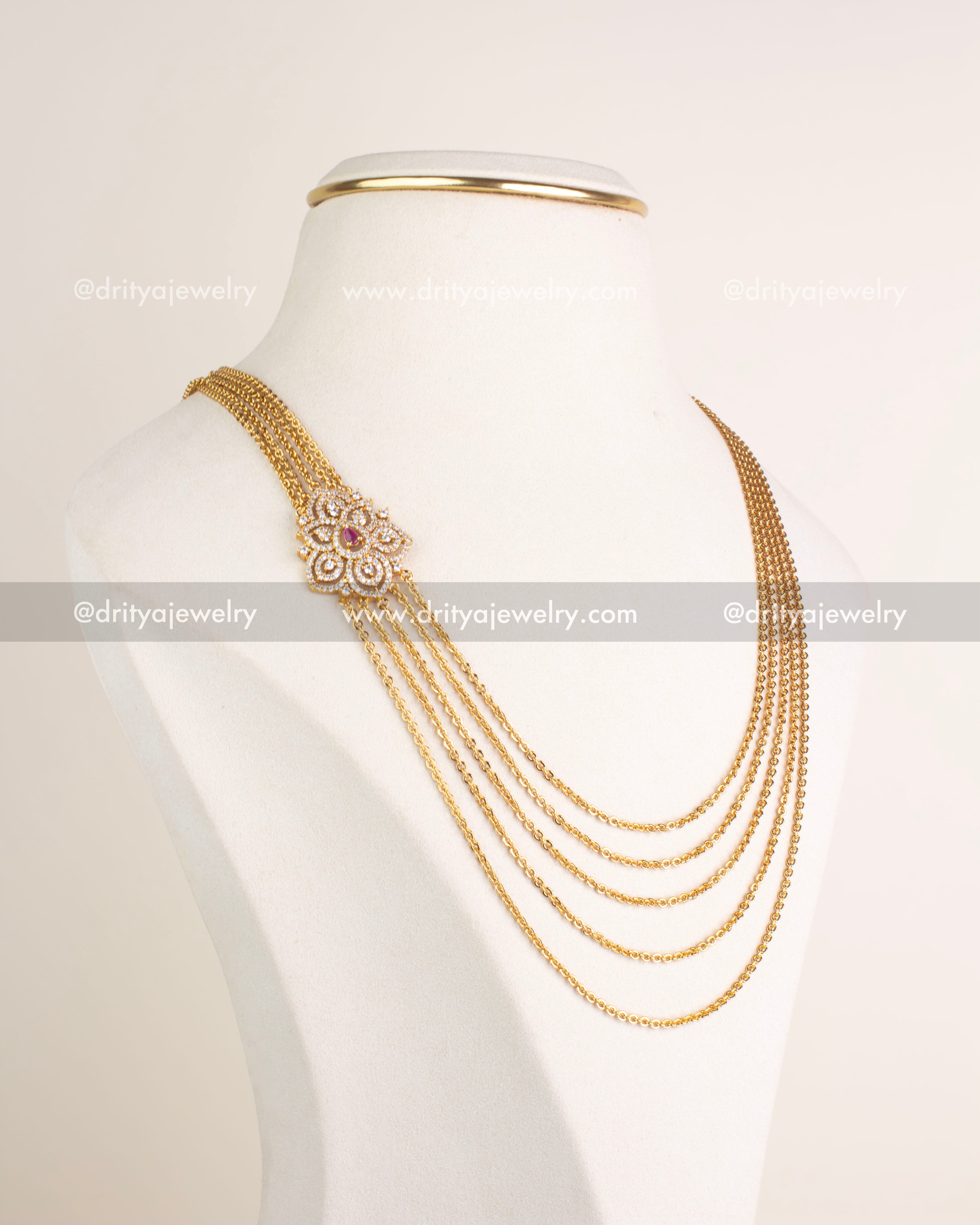 Angled view of layered micro-plated chandrahaar necklace with ruby accented CZ pendant