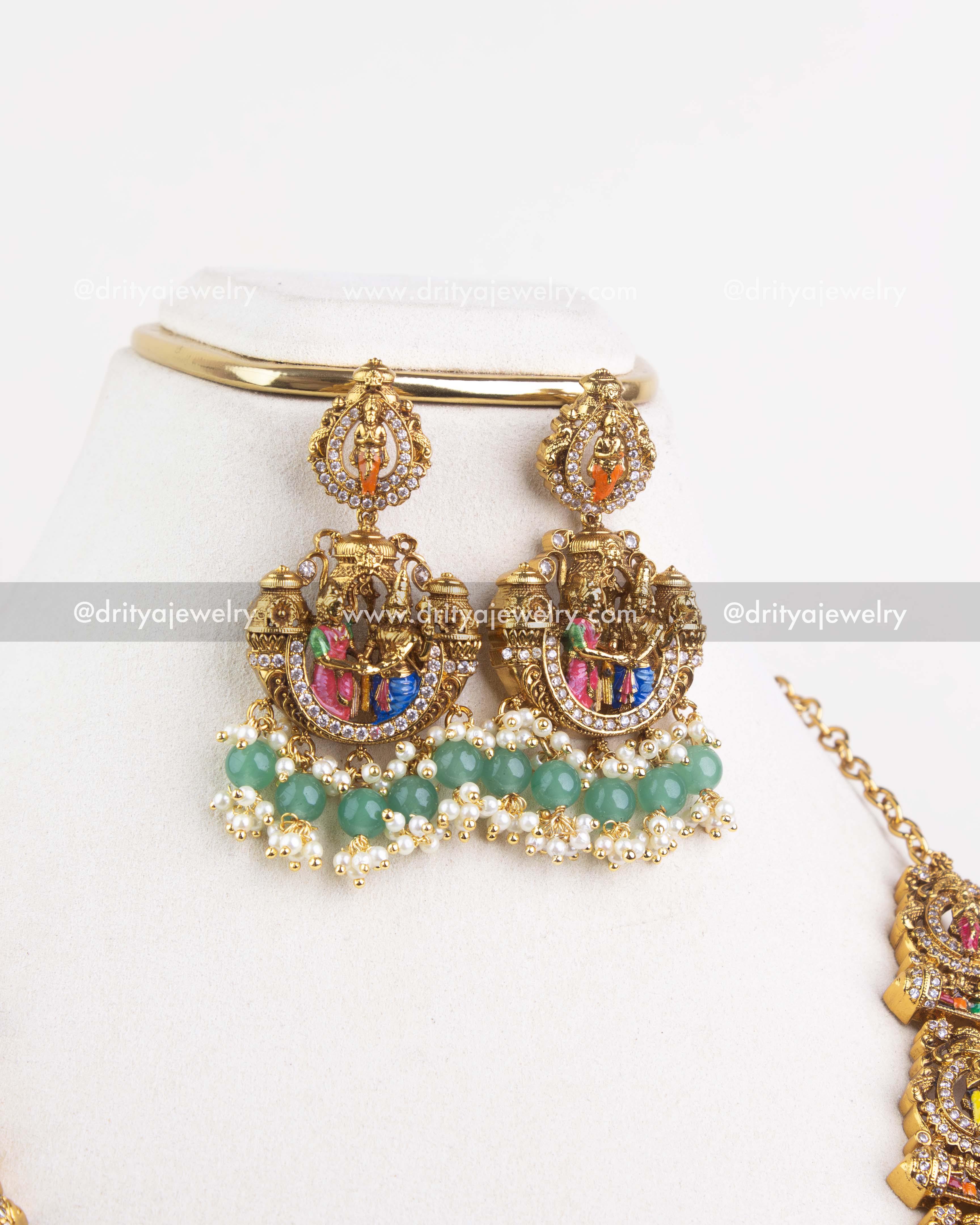 Close-up of matching temple earrings with meenakari work and green bead drops