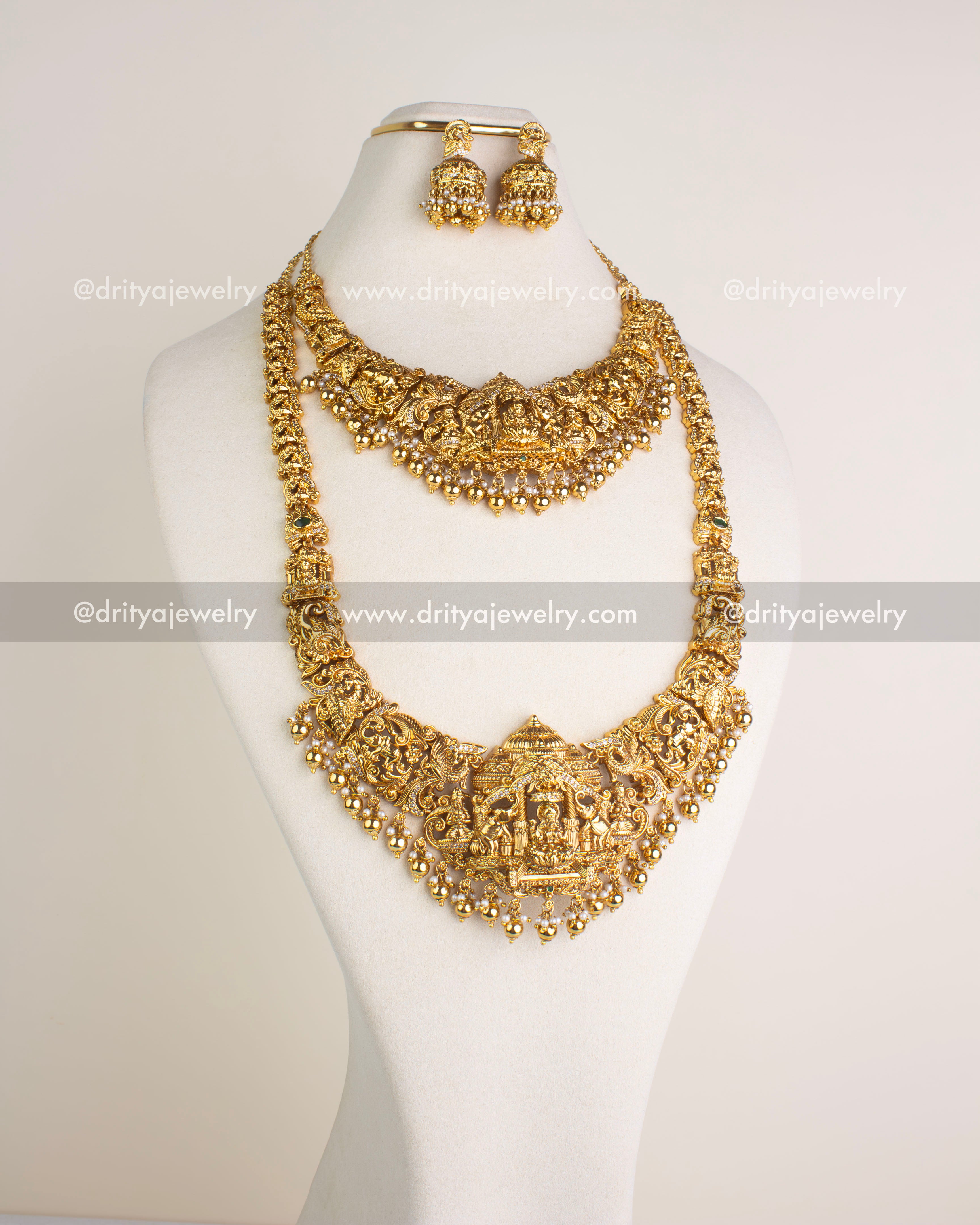 SKU 1124 - Necklace Set - Front view of gold-toned temple necklace set with god idol pendant and jhumka earrings on bust.