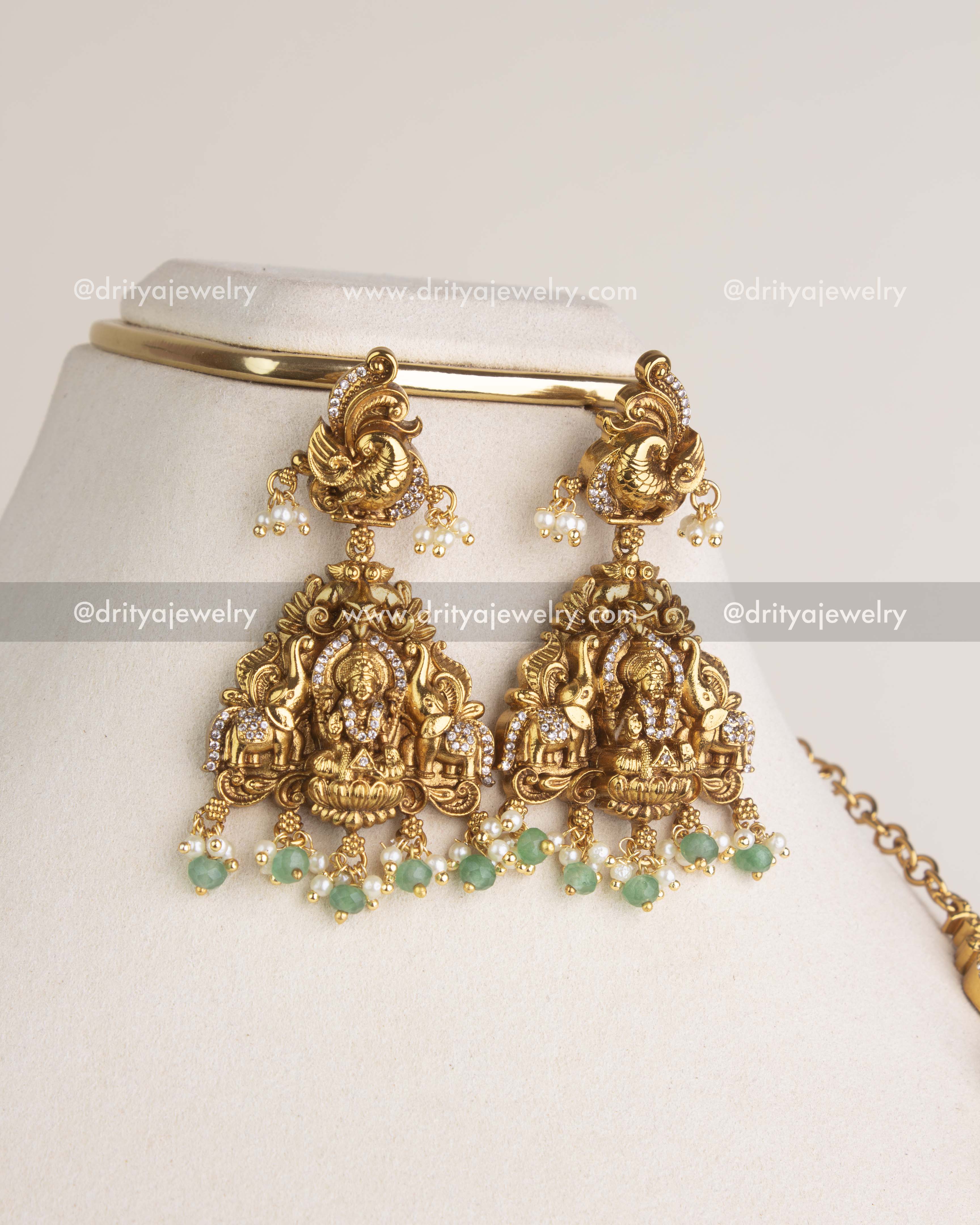 SKU 1178 Necklace Set close-up of god idol earrings with green bead drops on display stand